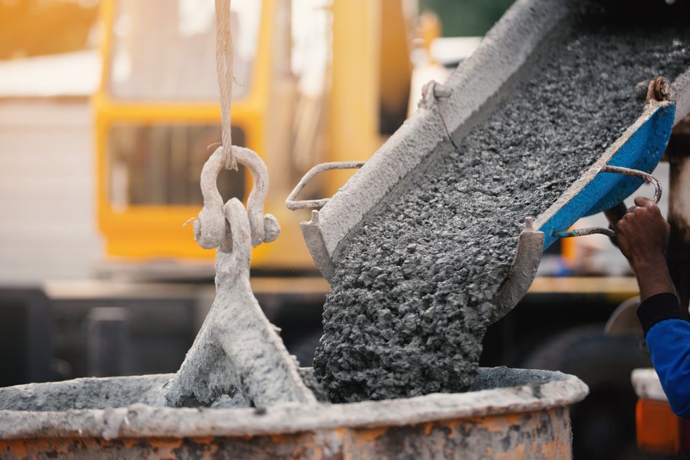 Concrete Being Poured From a Bucket Into Another at a Construction Site — Nambucca Concrete Pumping in Valla, NSW