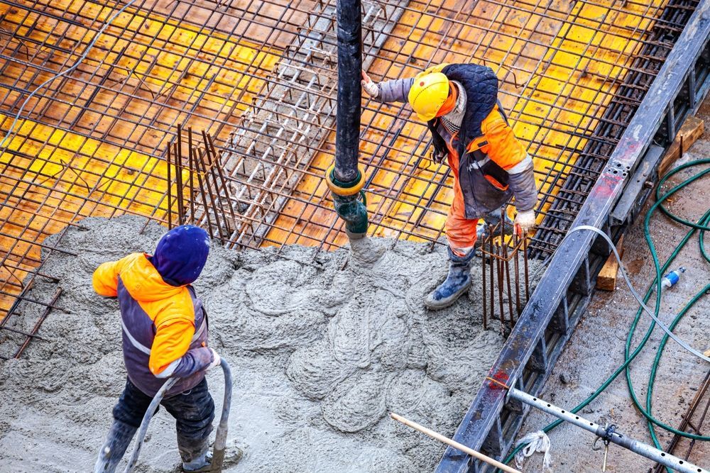 Two Construction Workers Pouring Concrete at a Building Site — Nambucca Concrete Pumping in Port Macquarie, NSW