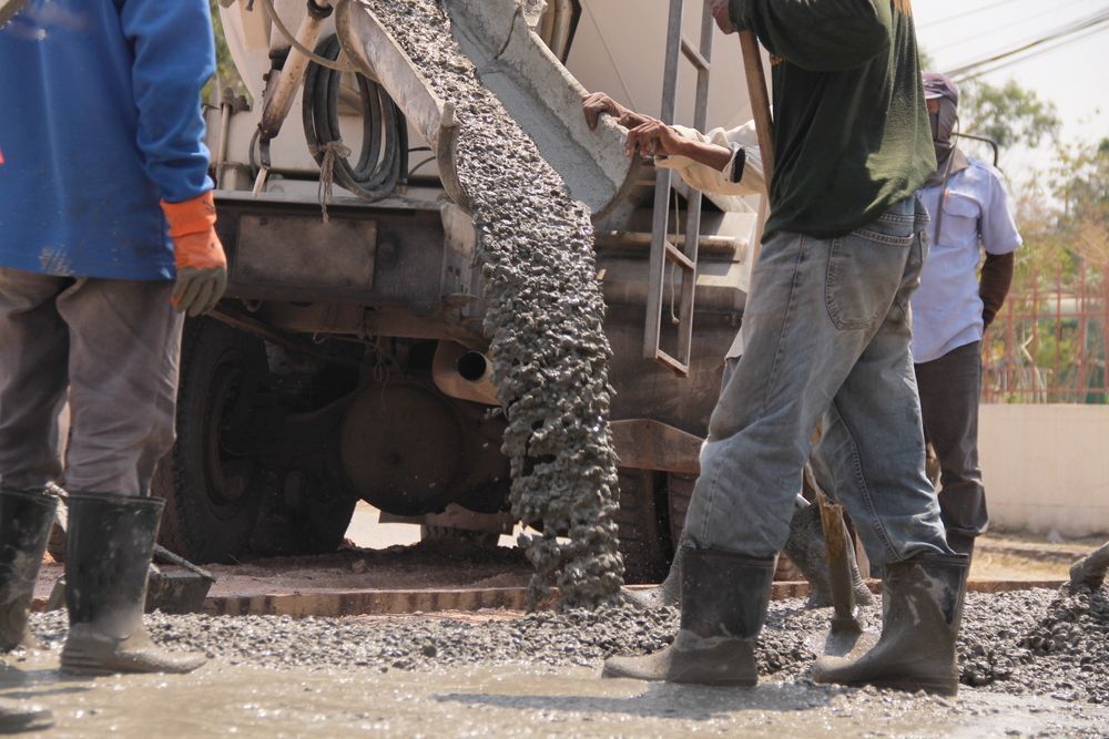 Workers Pouring Concrete From a Truck Mixer Onto a Road — Nambucca Concrete Pumping in Macksville, NSW