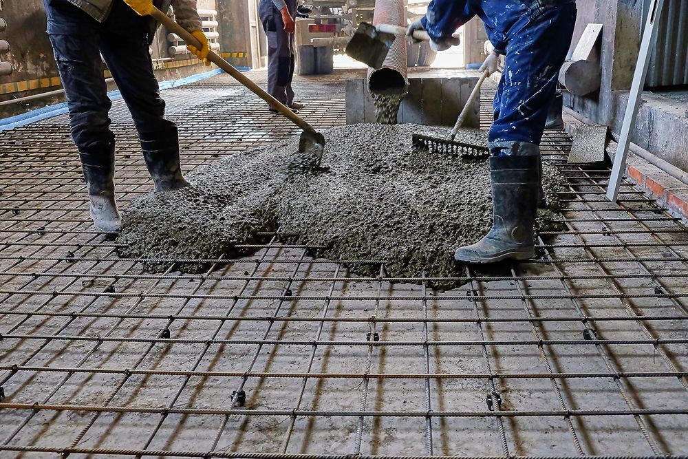 Workers Pouring and Spreading Concrete on a Rebar Grid, Construction Site — Nambucca Concrete Pumping in Valla, NSW