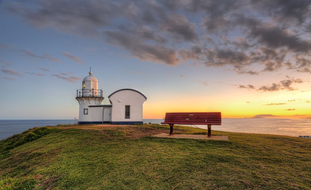 Lighthouse on a Grassy Cliff at Sunset With a Bench — Nambucca Concrete Pumping in Port Macquarie, NSW