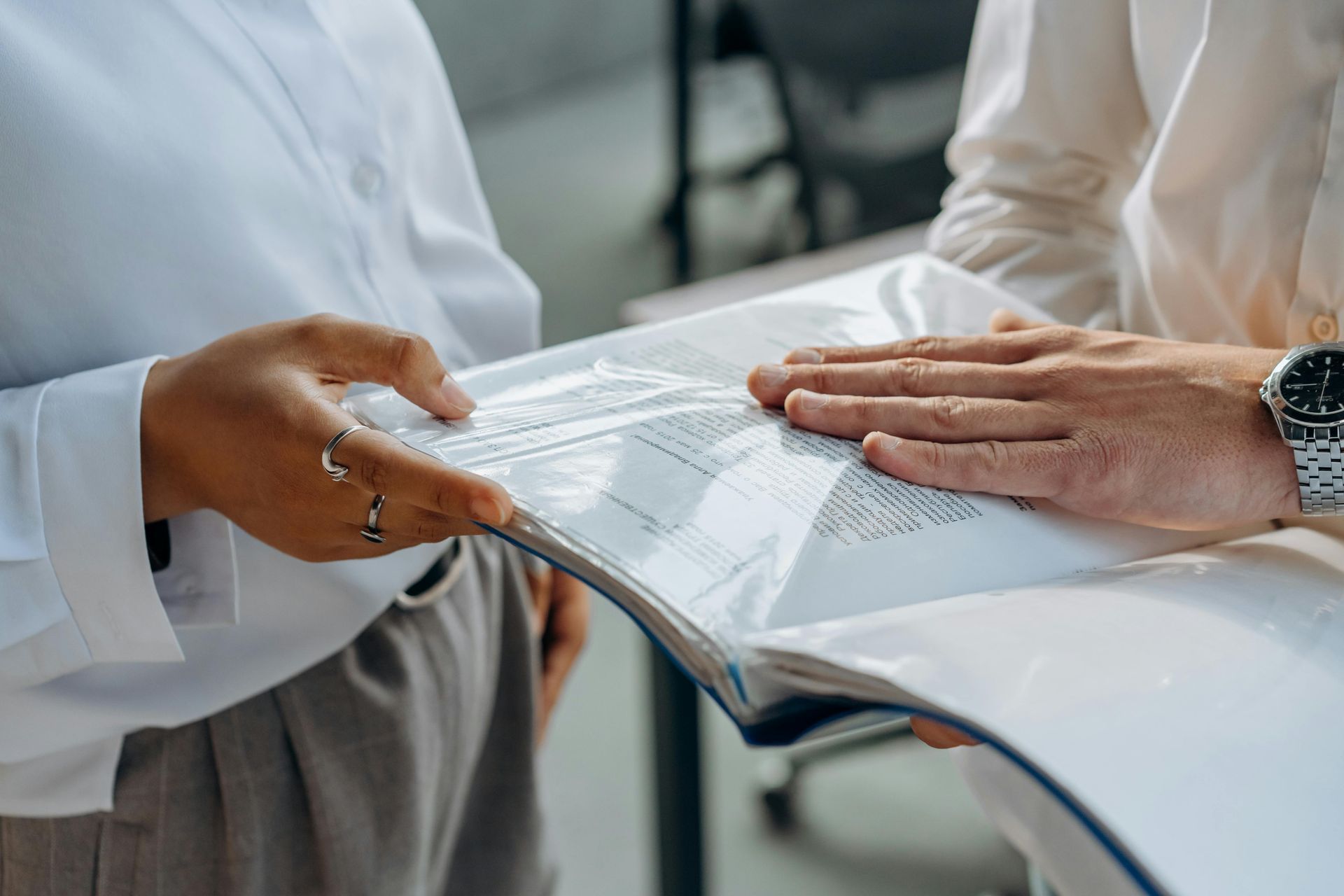 Two people in business attire reviewing documents in a binder.