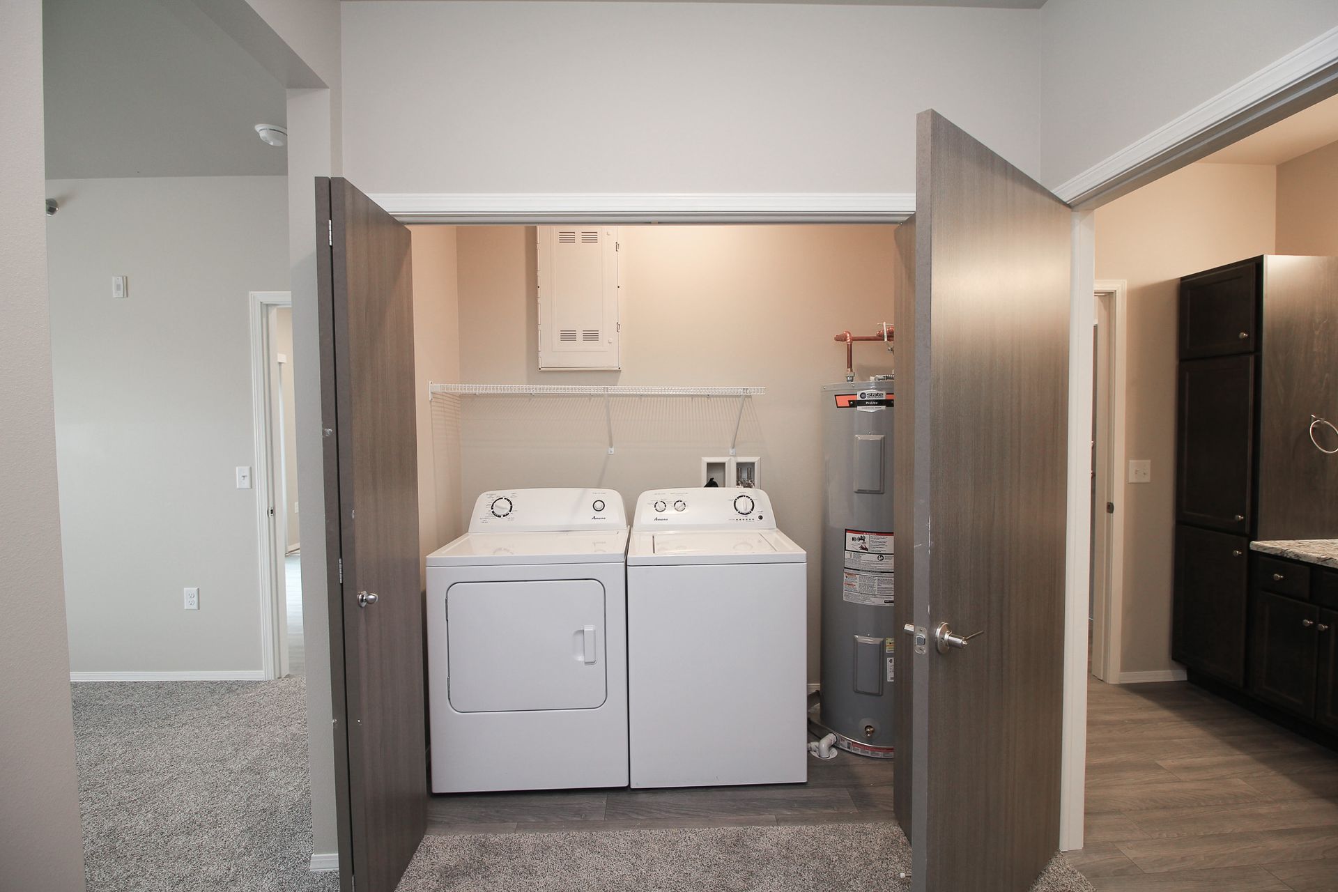 Laundry room with white washer and dryer in a closet, doors open