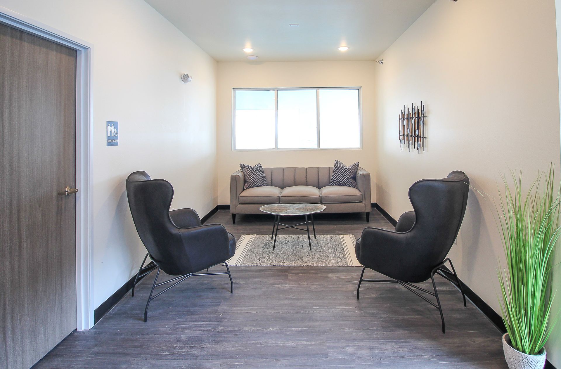 Modern living room with two black chairs, beige sofa, rug, and a window in soft natural light