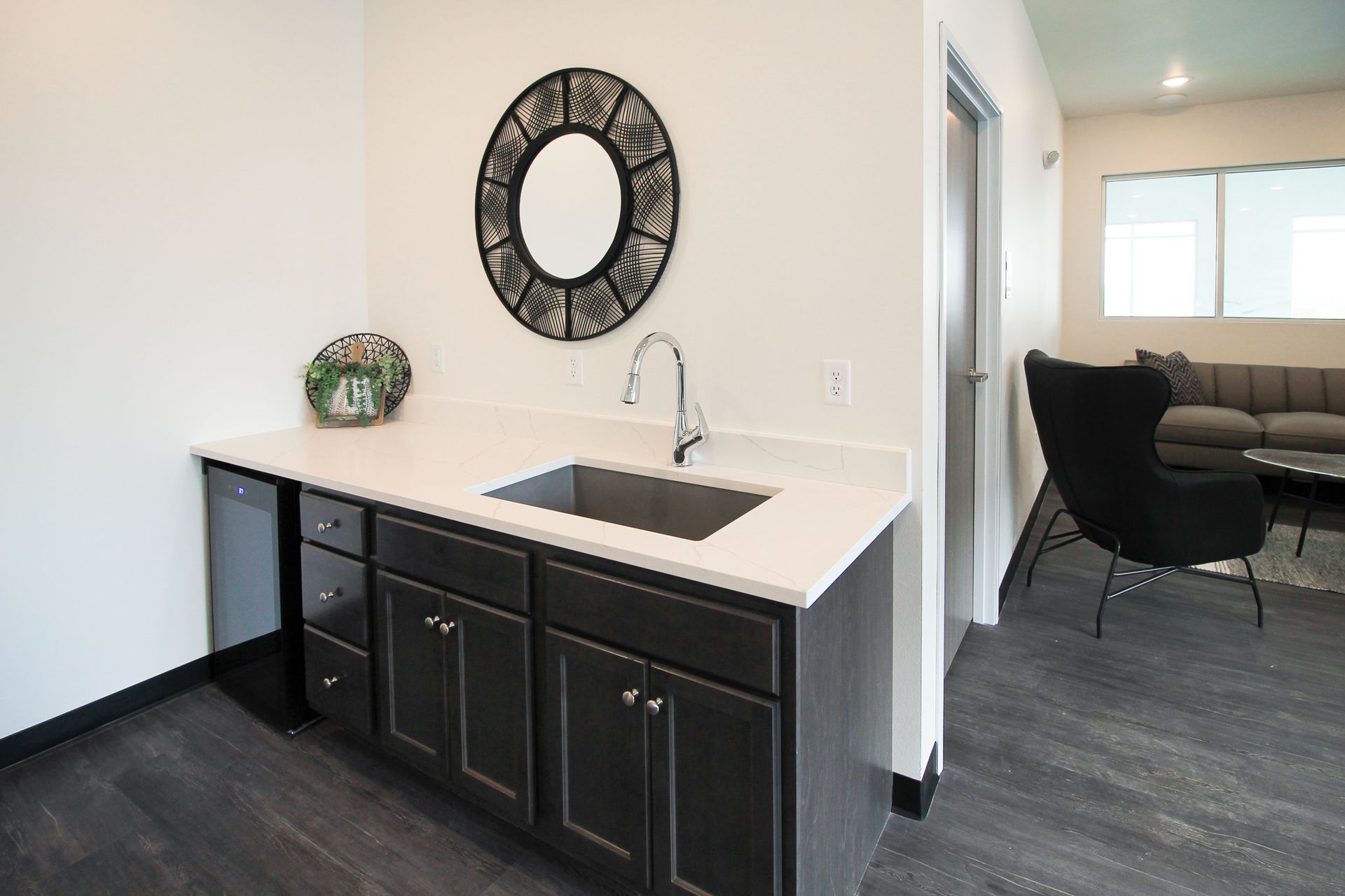 Compact black cabinet with sink and round mirror in a bright modern room