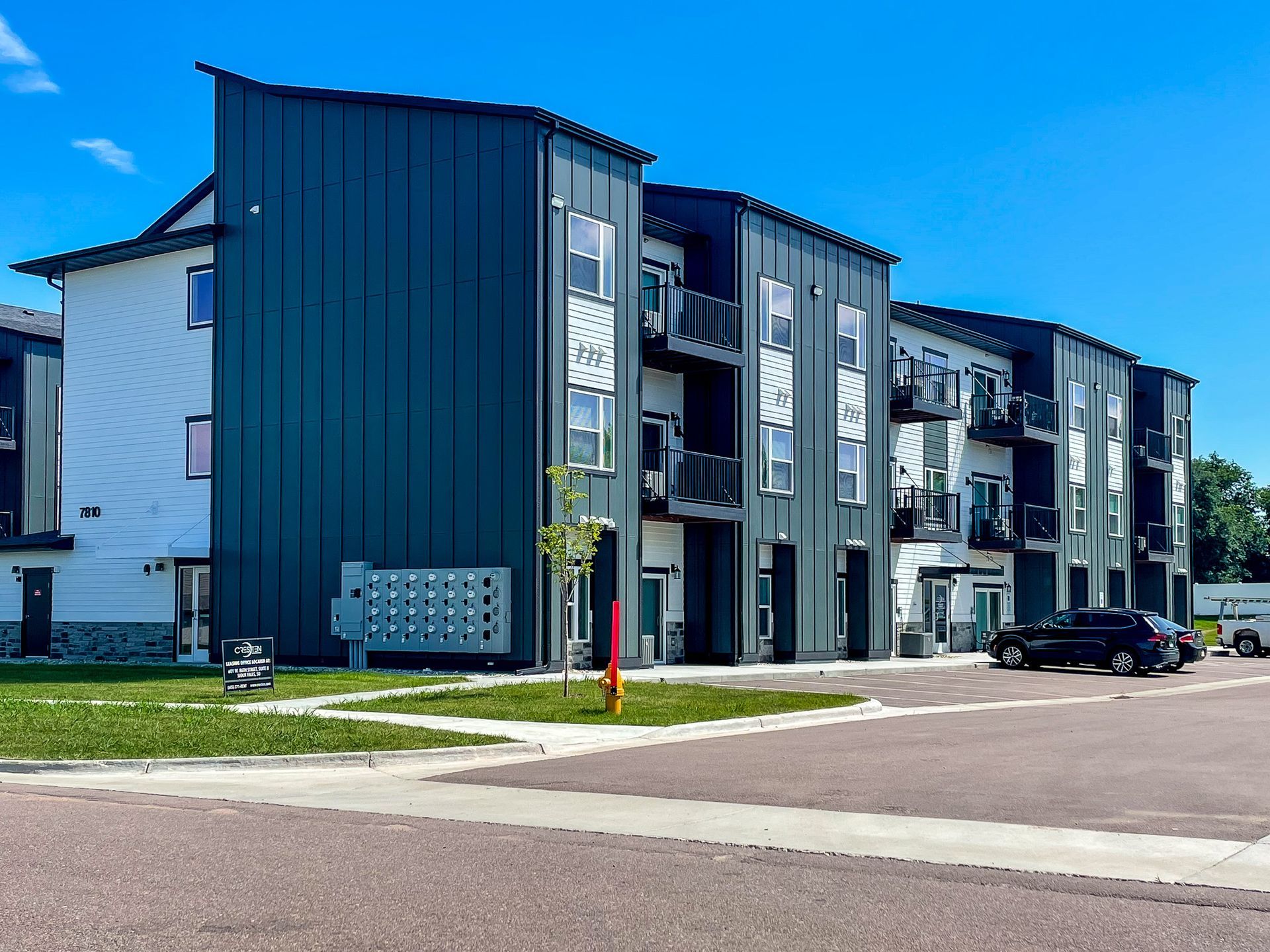 Modern apartment building with dark blue and gray siding on a sunny street corner