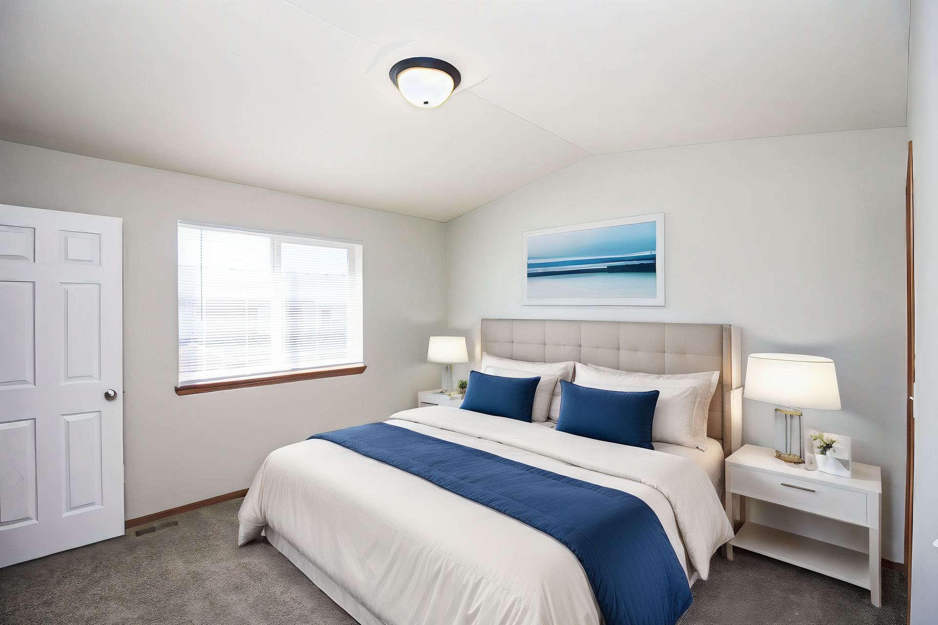 Bright bedroom with white walls, a neatly made bed, blue accents, and a bedside lamp by the window.