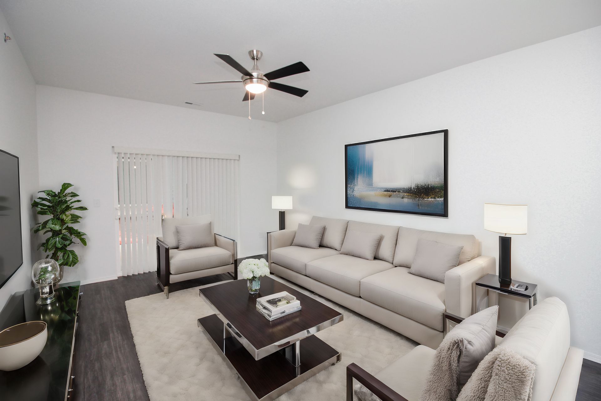 Bright modern living room with gray sectional sofa, armchair, coffee table, floor lamps, and wall art.