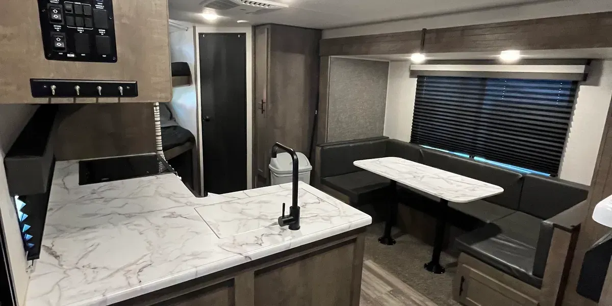 A kitchen in a rv with a table and a sink.