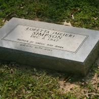 A grave marker on grass engraved with: Loretta (Meier) Simpson, Dec 2, 1947, Mother of Greg and Mark, With Jesus.