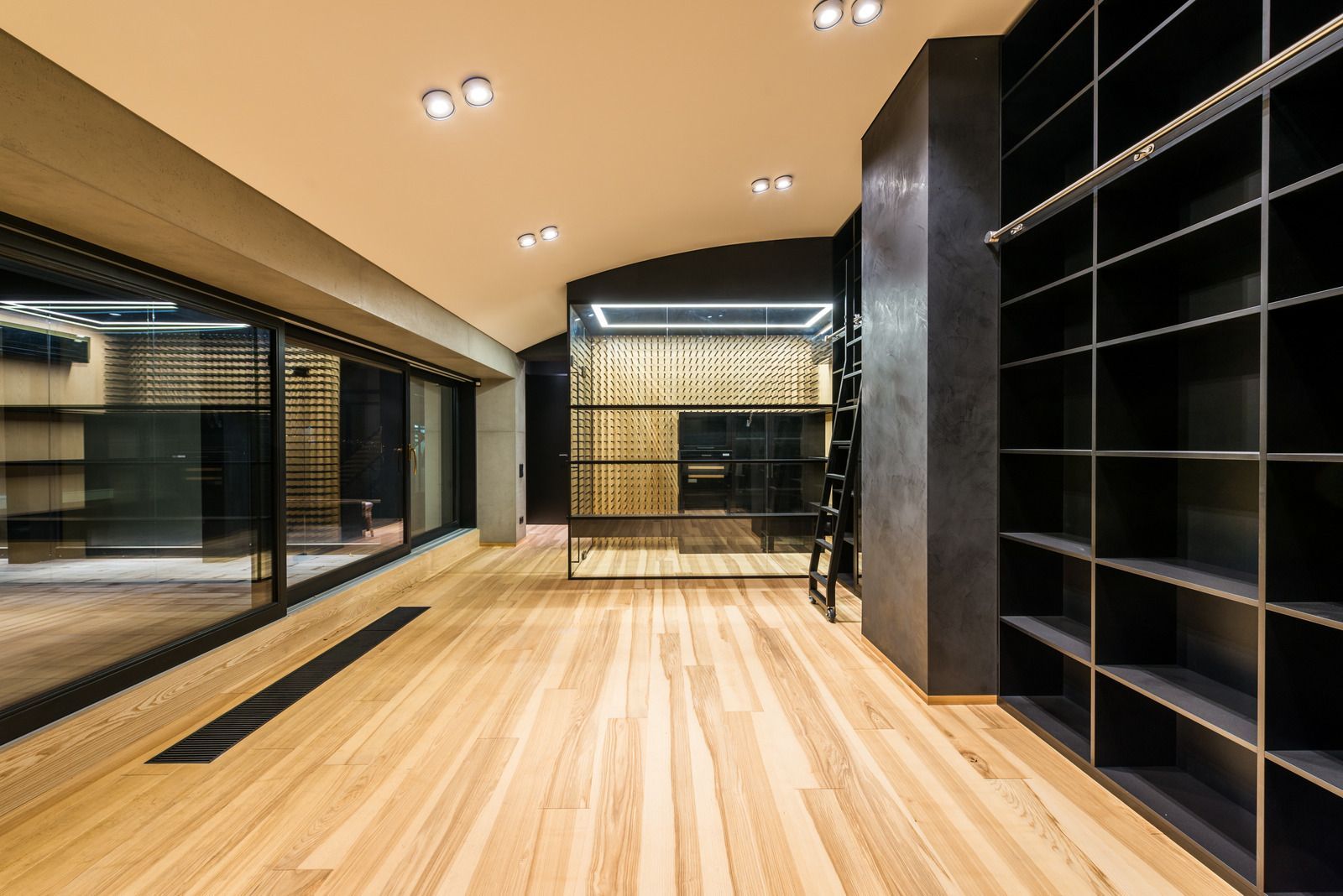 Modern walk-in closet with light wood floors, black shelving, mirrors, and ceiling lights