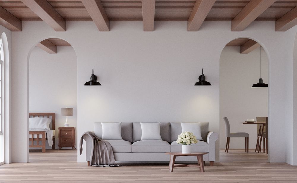 Minimalist living room with a gray sofa, wooden coffee table, pendant lights, and arched doorways