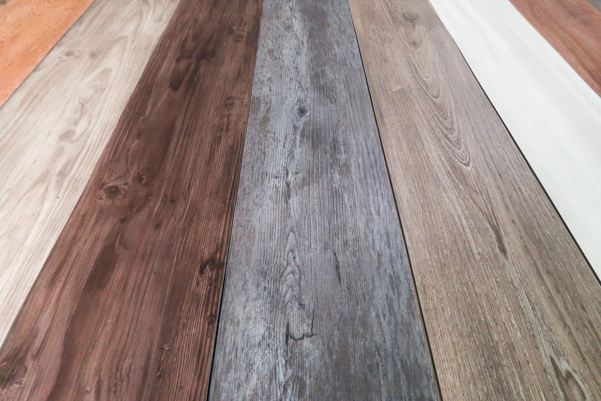 Wood-look vinyl planks in varied gray, brown, and beige tones arranged in long strips