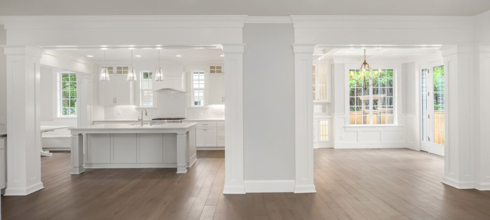 Bright open-plan living space with white walls, hardwood floors, and a large kitchen island.