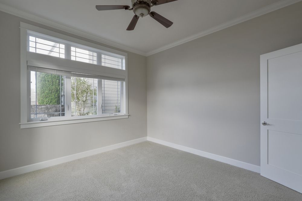 Empty gray bedroom with window, ceiling fan, and white closet door