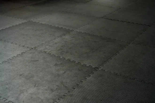 Gray textured foam floor mats with interlocking seams arranged in a grid.