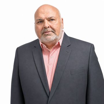 Portrait of a bald man in a dark blazer and pink shirt against a white background
