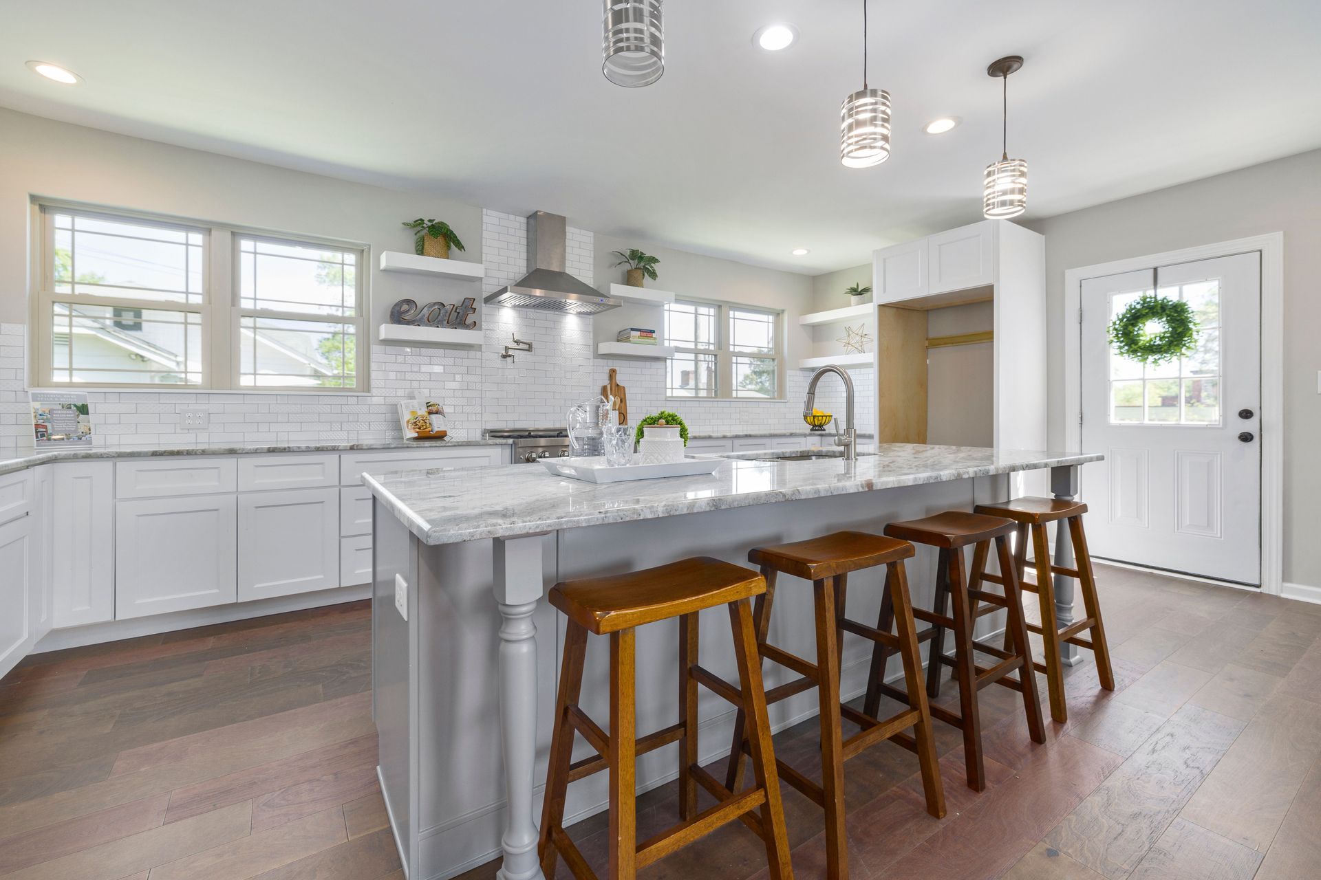 Bright modern kitchen with white cabinets, large island, and wooden bar stools