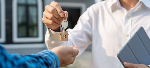 Handing over house keys during a property sale, with a tablet nearby