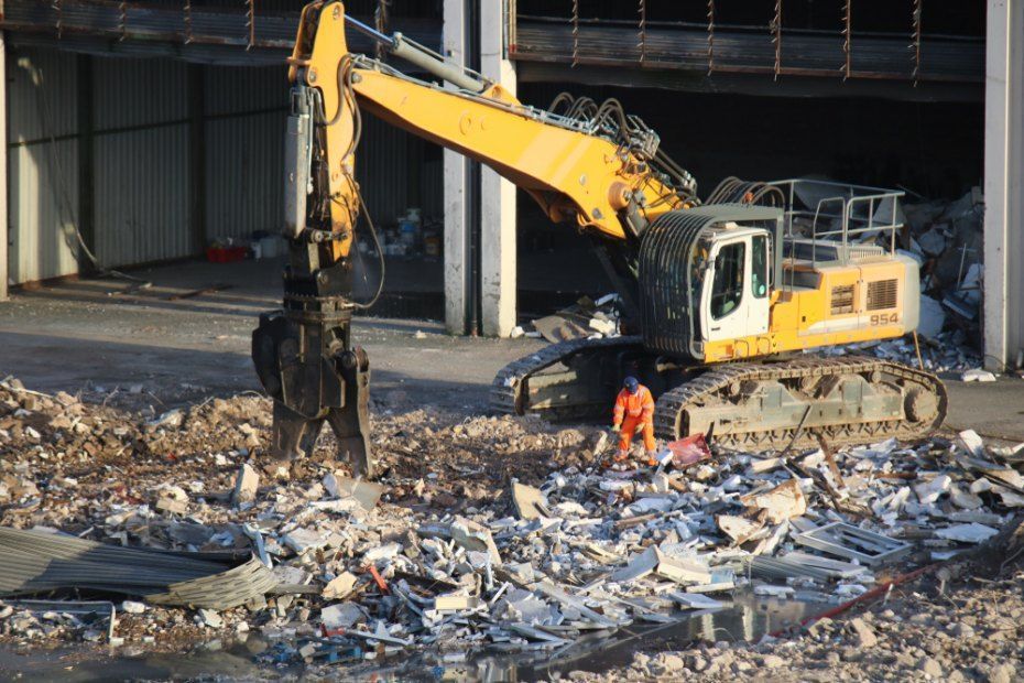 A Large Yellow Excavator is Demolishing a Building — Bennettron Demex in Kempsey, NSW