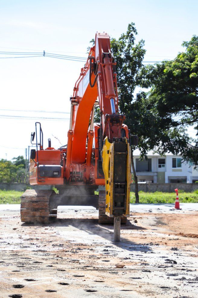 A Large Orange Excavator is Working on a Dirt Road — Bennettron Demex in Byron Bay, NSW