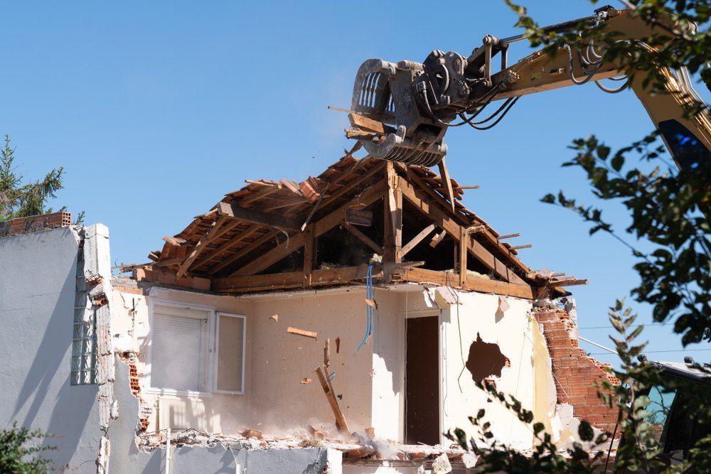 A house is being demolished by a large excavator — Bennettron Demex in Corindi Beach, NSW