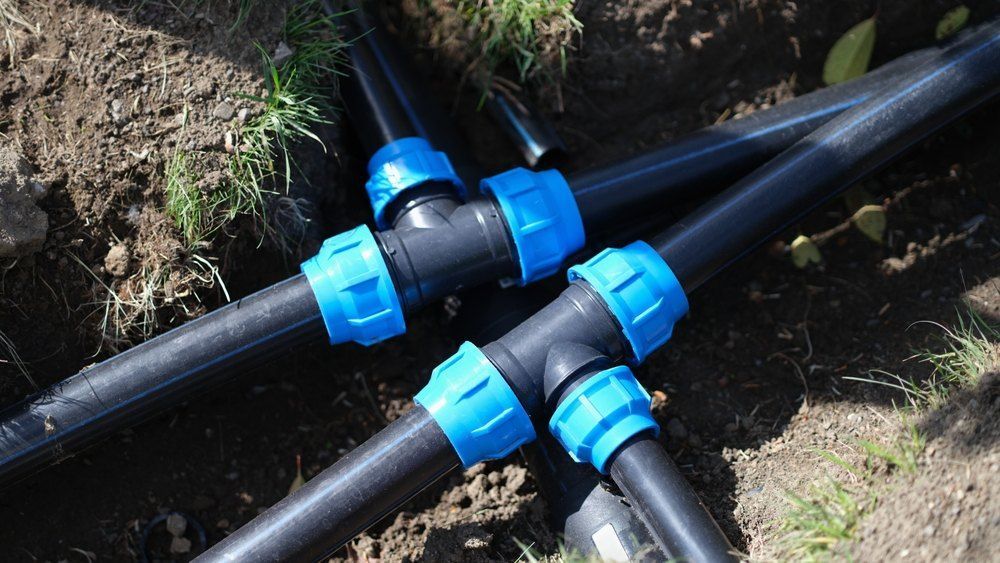 A Bunch of Black Pipes With Blue Connectors Are Laying in the Dirt — Bennettron Demex in Bonville, NSW