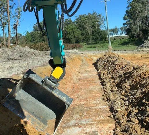 A Green and Yellow Excavator is Digging a Hole in the Dirt — Bennettron Demex in Corindi Beach, NSW