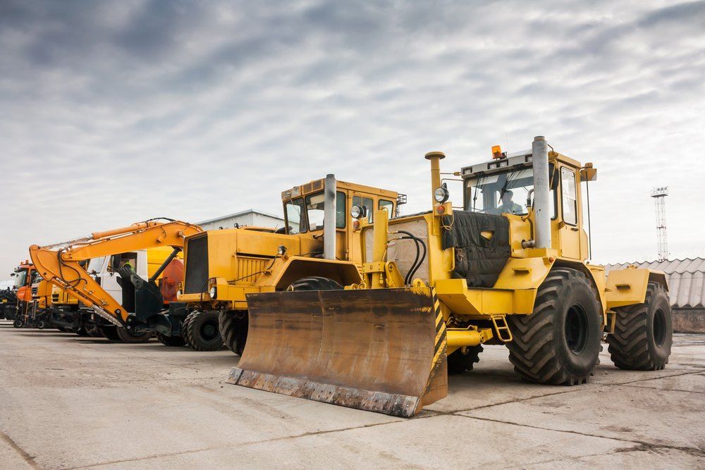 A Row of Yellow Construction Vehicles Are Parked in a Parking Lot — Bennettron Demex in Woolgoolga, NSW