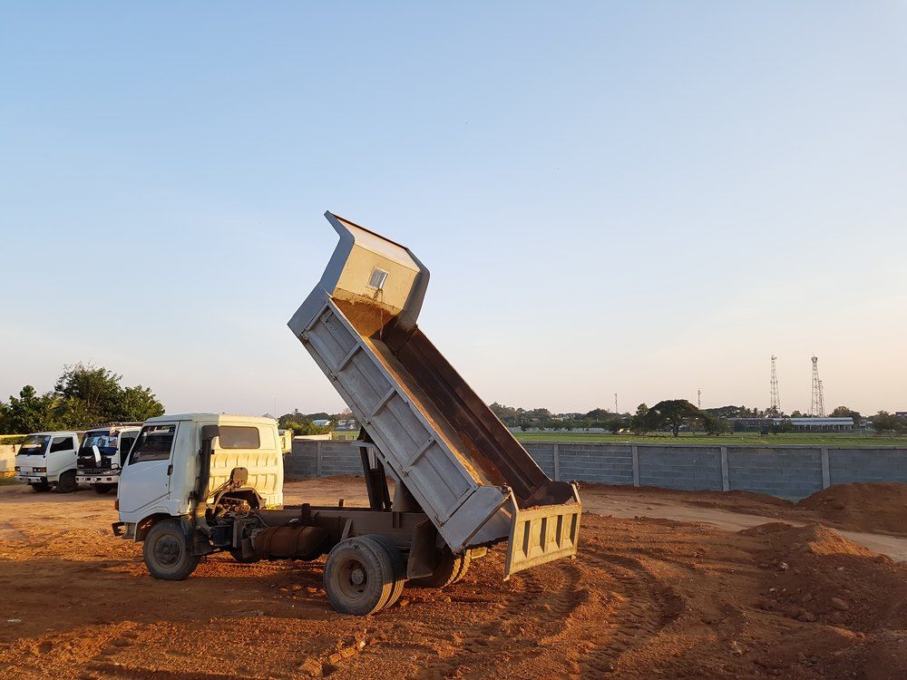 A Dump Truck is Parked in a Dirt Lot With Its Bed Open — Bennettron Demex in Ballina, NSW