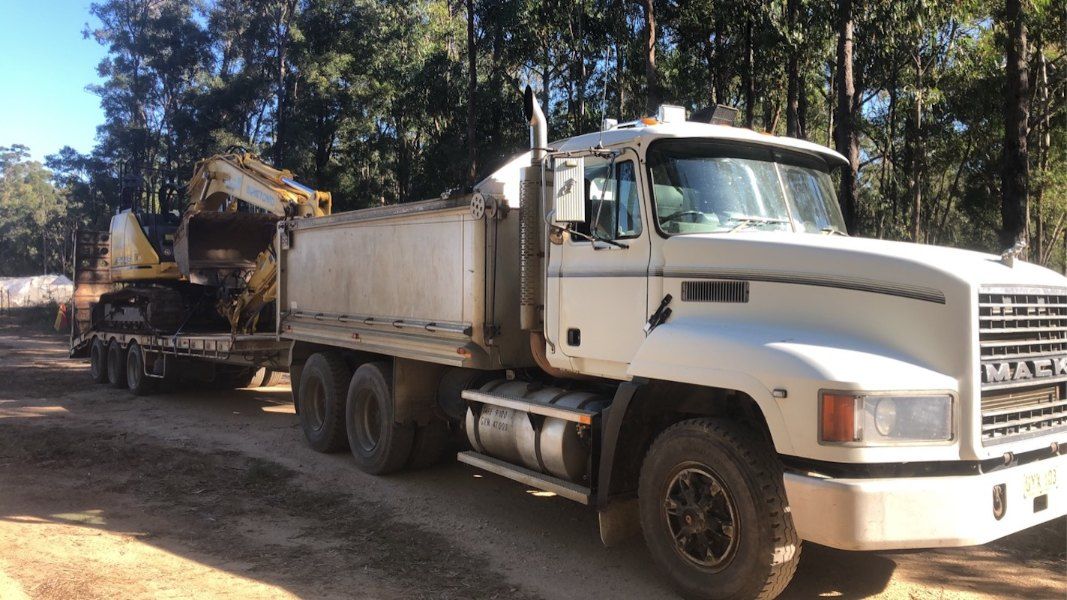 A Dump Truck With a Trailer Attached to It is Parked on a Dirt Road — Bennettron Demex in Corindi Beach, NSW