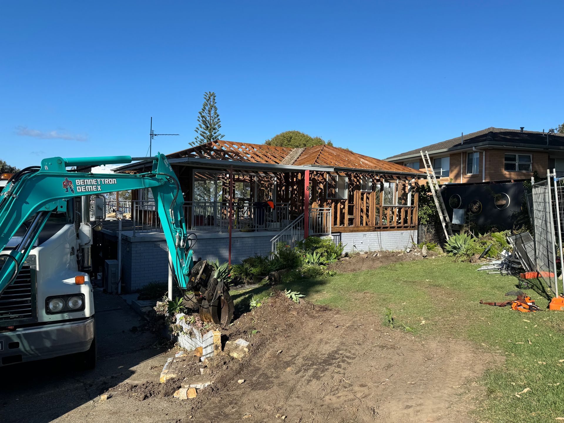 A Old house with wooden frames is on lawn with Blue digger— Bennettron Demex in Corindi Beach, NSW