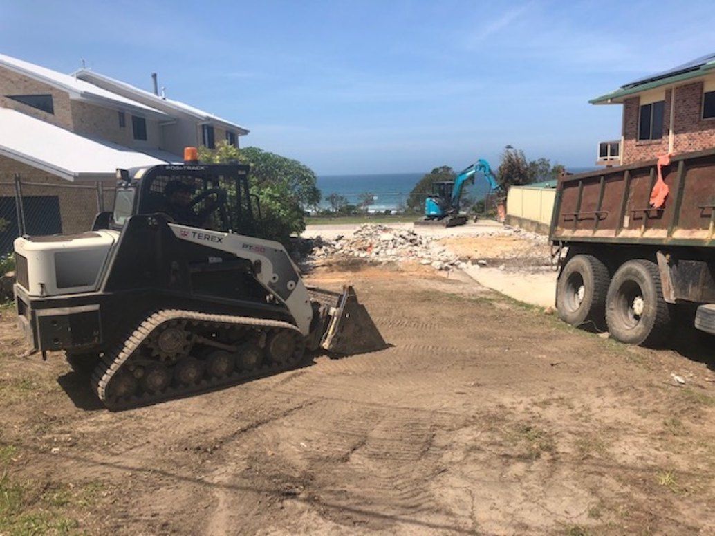 A Bulldozer is Driving Down a Dirt Road Next to a Dump Truck — Bennettron Demex in Ulmarra, NSW