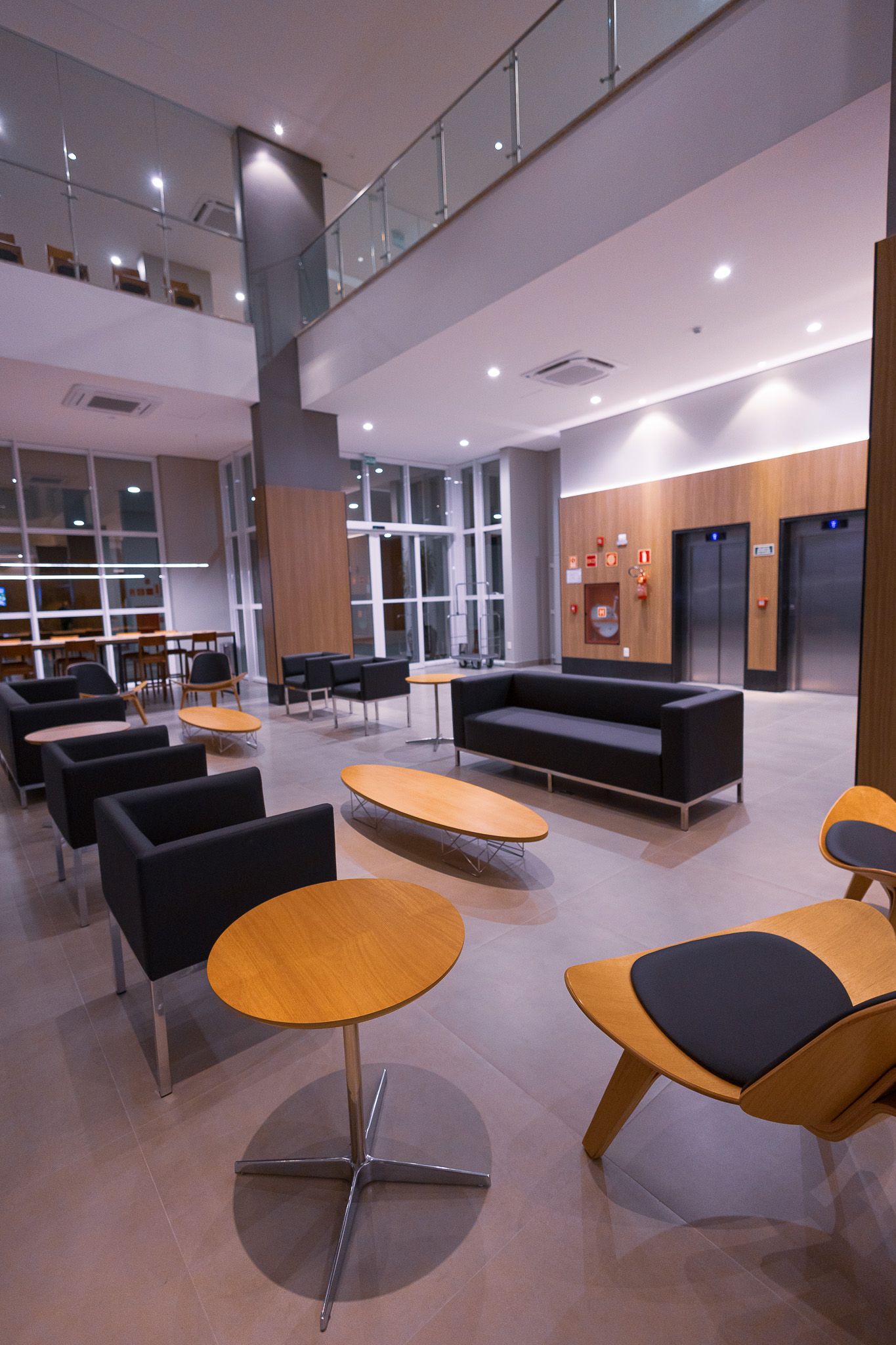 Sala de estar com sofá modular de couro preto, poltrona listrada e cortinas em tons neutros.
