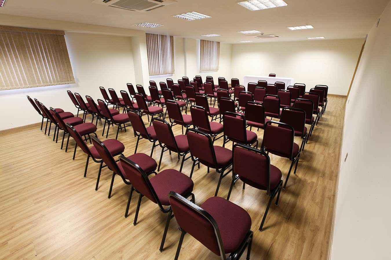 Sala de conferências com fileiras de mesas e cadeiras, toalhas de mesa azuis.