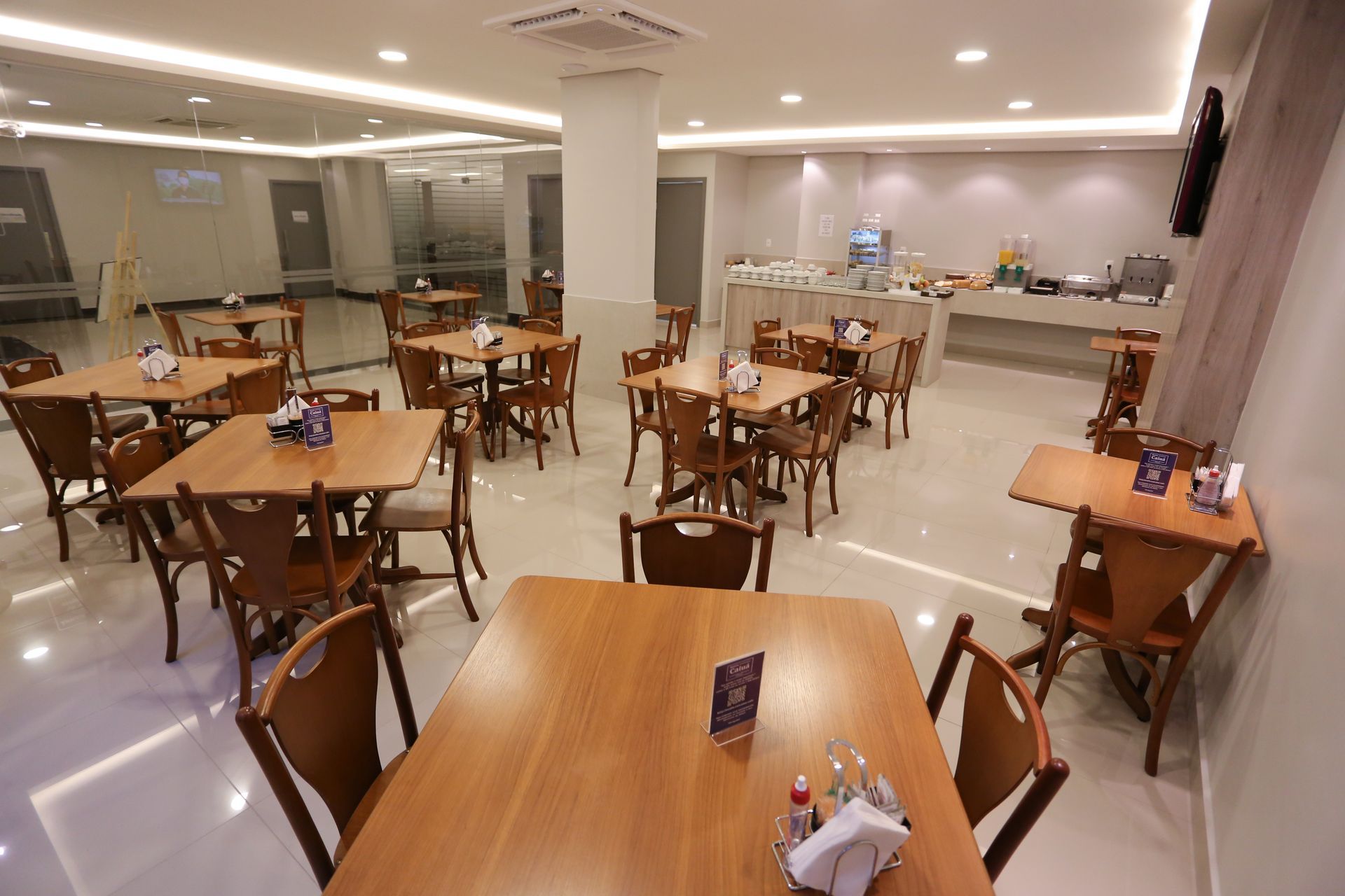 Sala de conferências preparada para uma reunião, com mesas dispostas em forma de U e cadeiras.