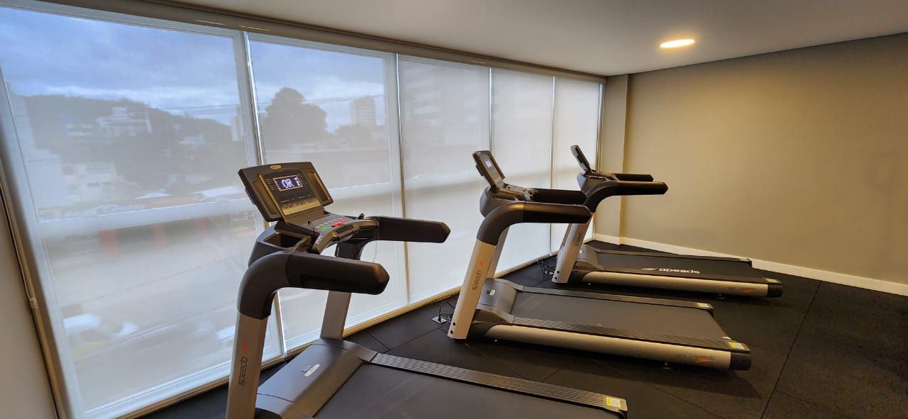 Duas esteiras ergométricas em uma academia residencial perto de uma janela com vista.
