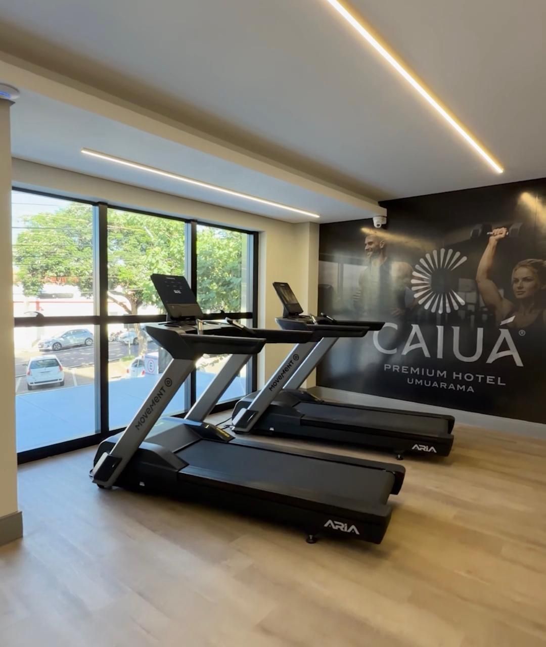 Sala de estar com sofá modular de couro preto, poltrona listrada e cortinas em tons neutros.