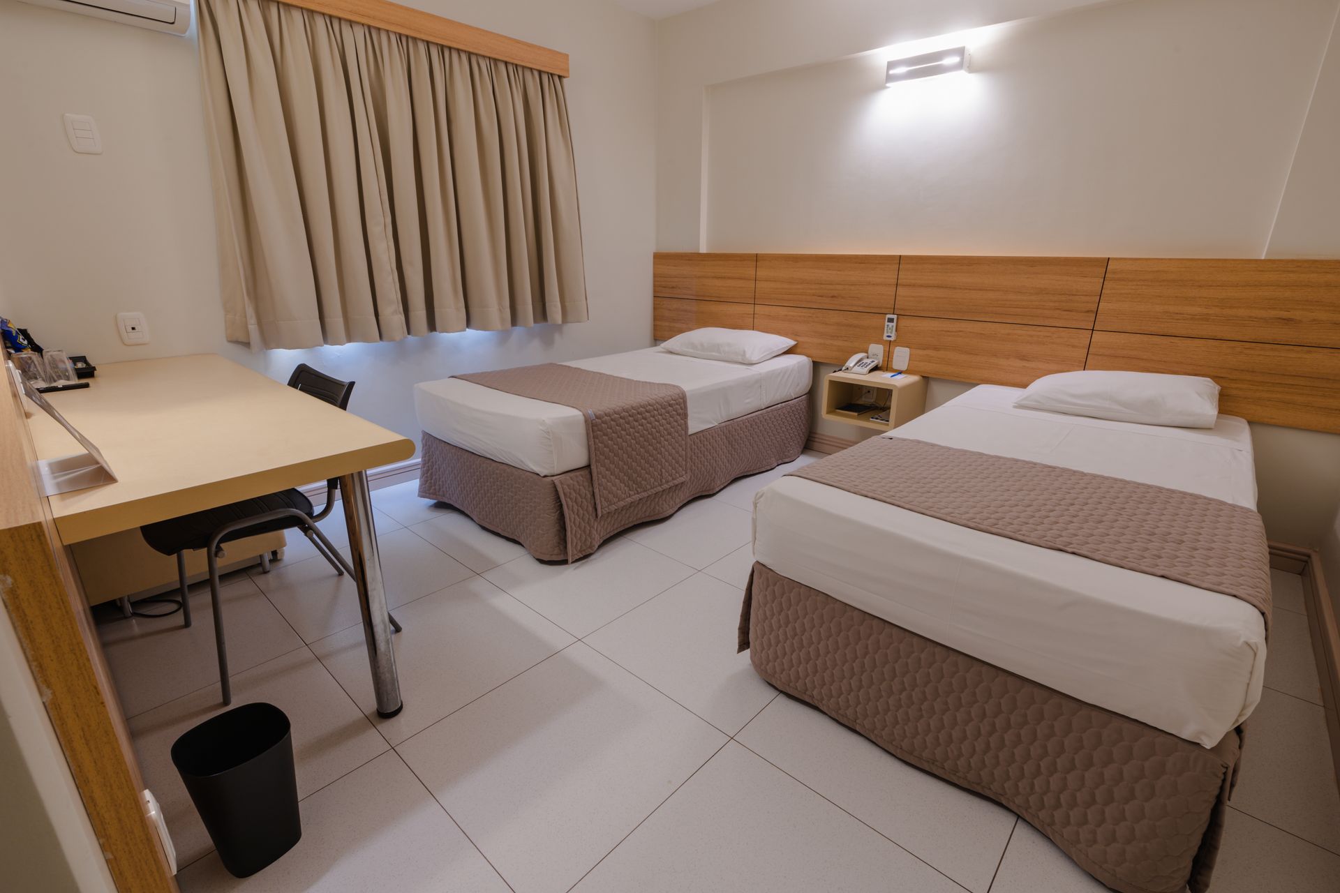 Sala de estar com sofá modular de couro preto, poltrona listrada e cortinas em tons neutros.