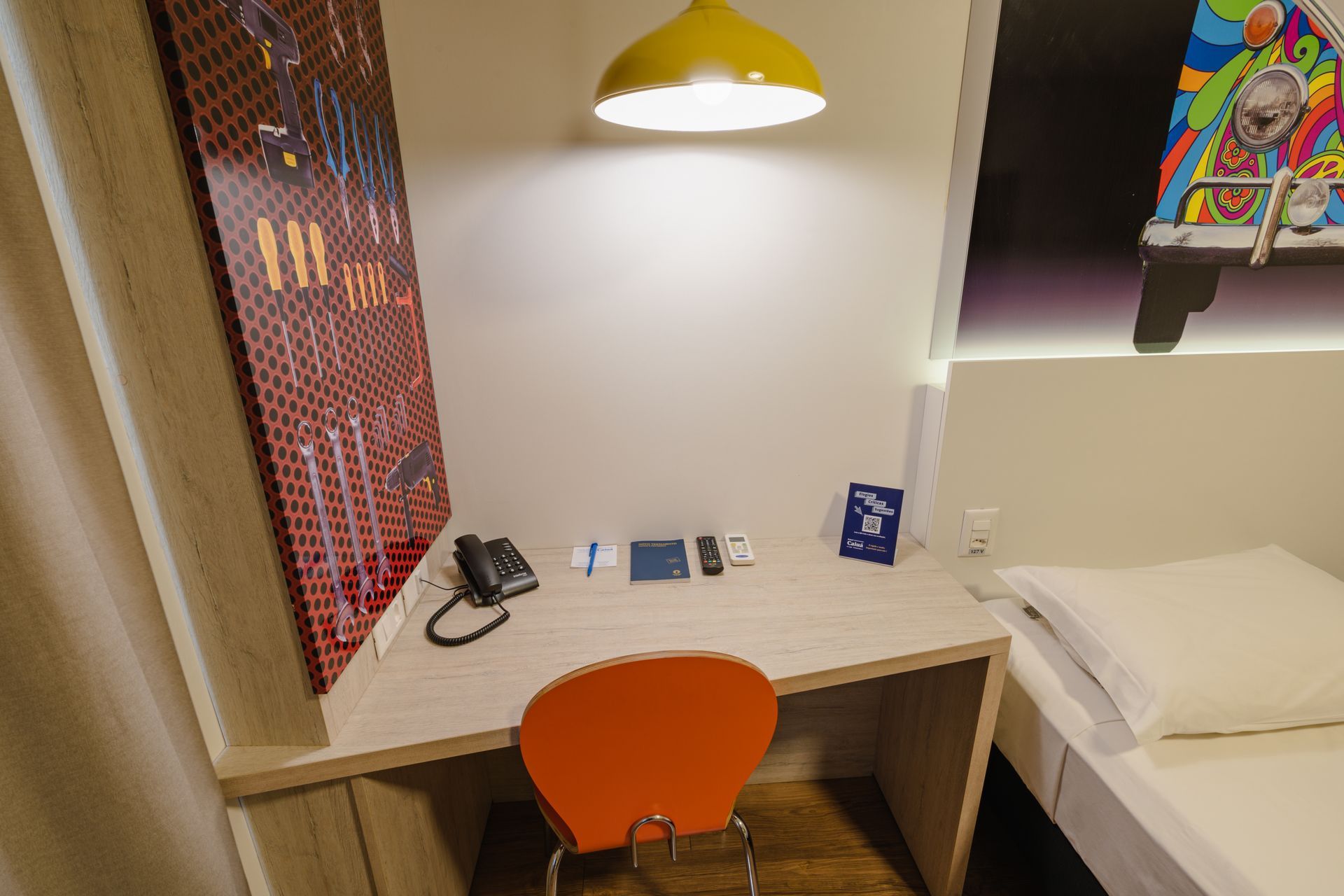 Sala de estar com sofá modular de couro preto, poltrona listrada e cortinas em tons neutros.