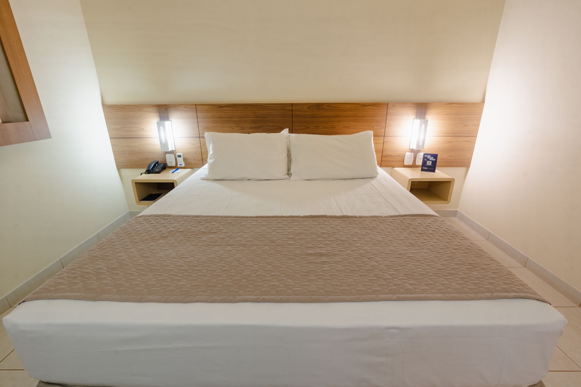 Sala de estar com sofá modular de couro preto, poltrona listrada e cortinas em tons neutros.