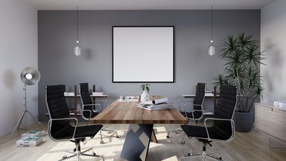 Modern conference room with black chairs, wood table, wall screen, and potted plant