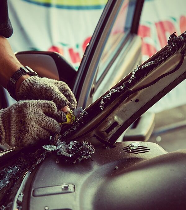 Gloved Hands Cleaning a Car Windshield With a Scraper and Cloth Near the Dashboard — Walker Bros. in Casino, NSW