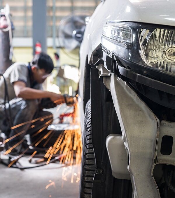 Mechanic Welding a White Car’s Front Bumper, Sparks Flying in a Garage — Walker Bros. in Casino, NSW