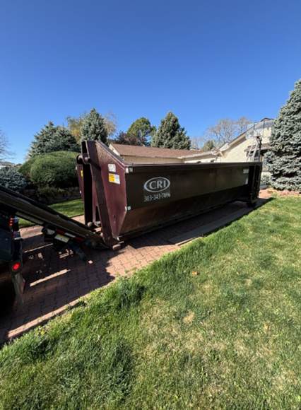 Construction site dumpster rental with roll-off container placed on residential driveway in Denver. Construction site dumpster rental with roll-off container placed on residential driveway in Denver.