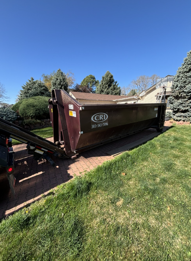 A dump truck parked beside a residential driveway, with grass and trees in the background. A dump truck parked beside a residential driveway, with grass and trees in the background.