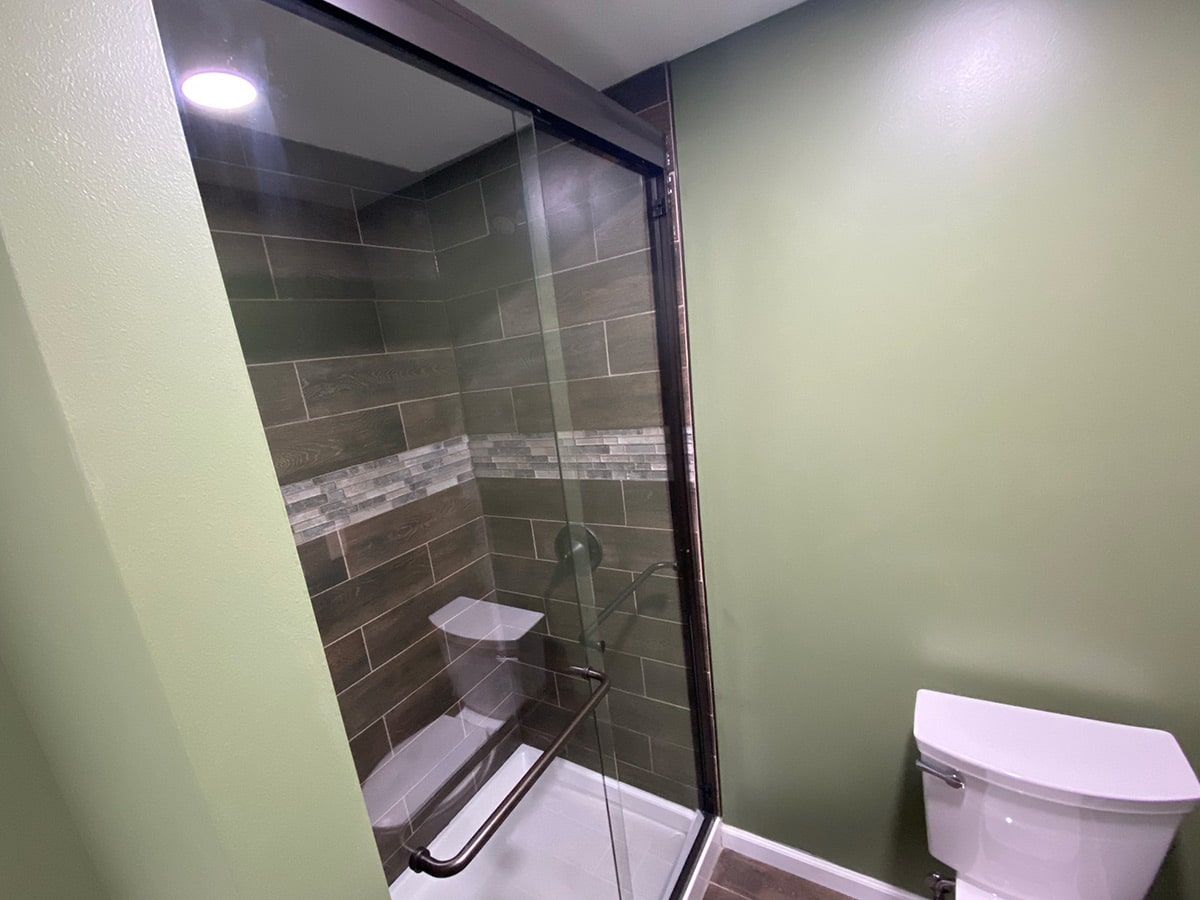 a bathroom with a toilet and a shower with a glass door .