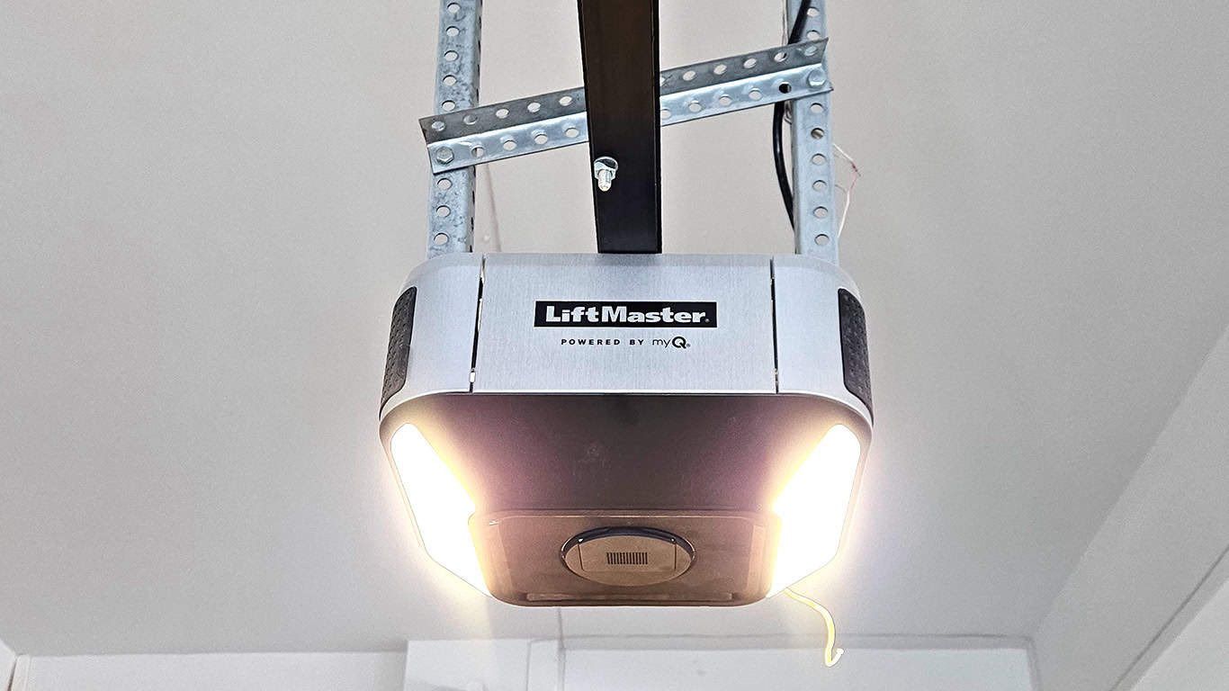 White garage door opener mounted to the ceiling, with bright lights shining downward