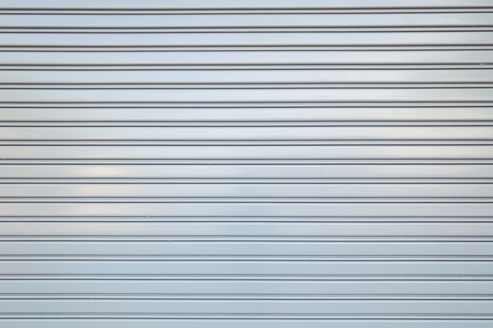 Horizontal gray metal shutter with evenly spaced slats and subtle reflections