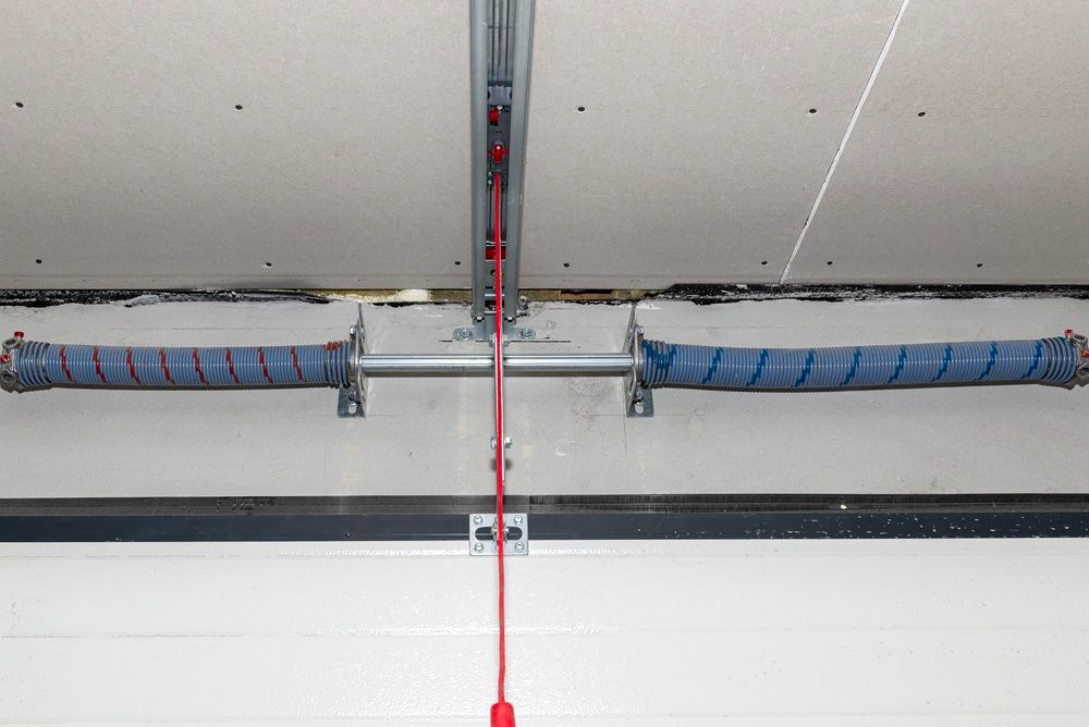 Ceiling-mounted garage door track with a red pull cord and blue insulation along both sides
